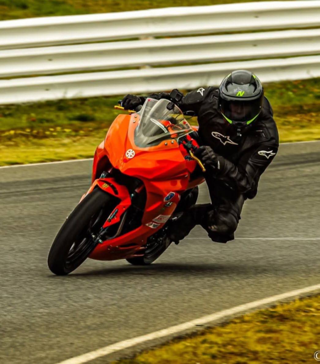 Rider on a bright orange sportbike carving a corner